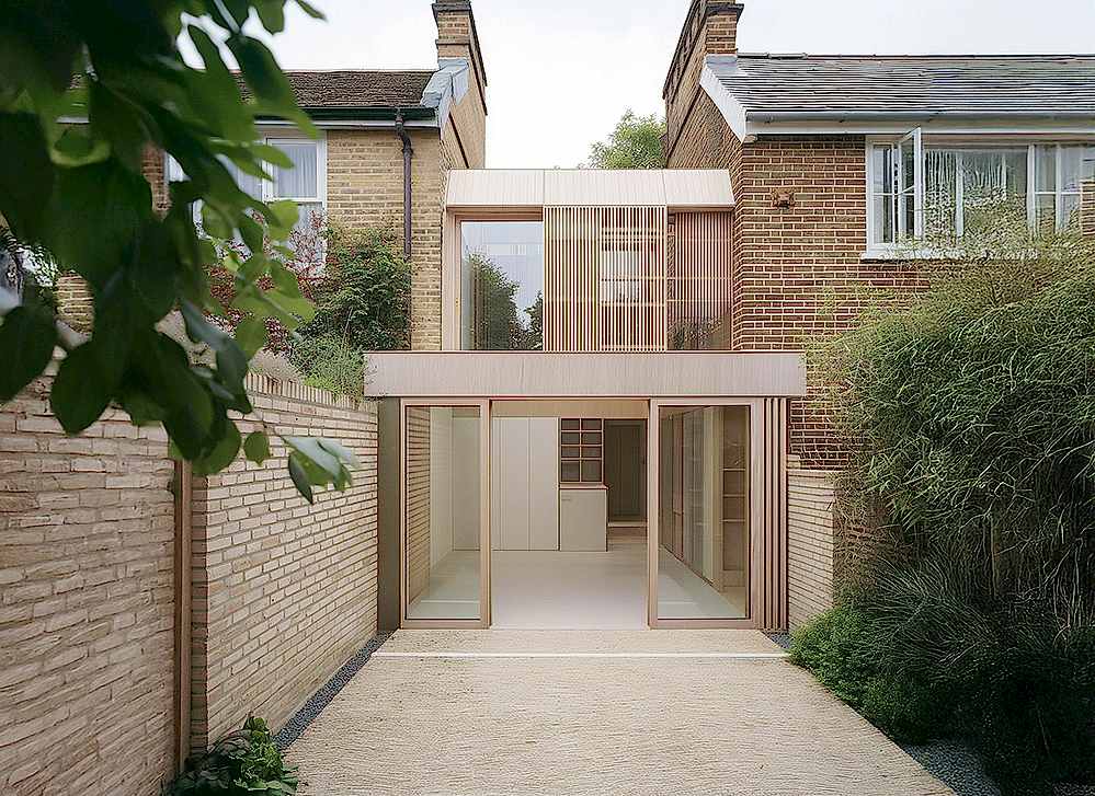 Rear view of a sustainable London home extension featuring timber cladding, large triple-glazed openings, and meticulous detailing, designed to meet EnerPHit principles for energy efficiency, airtightness, and occupant comfort.
