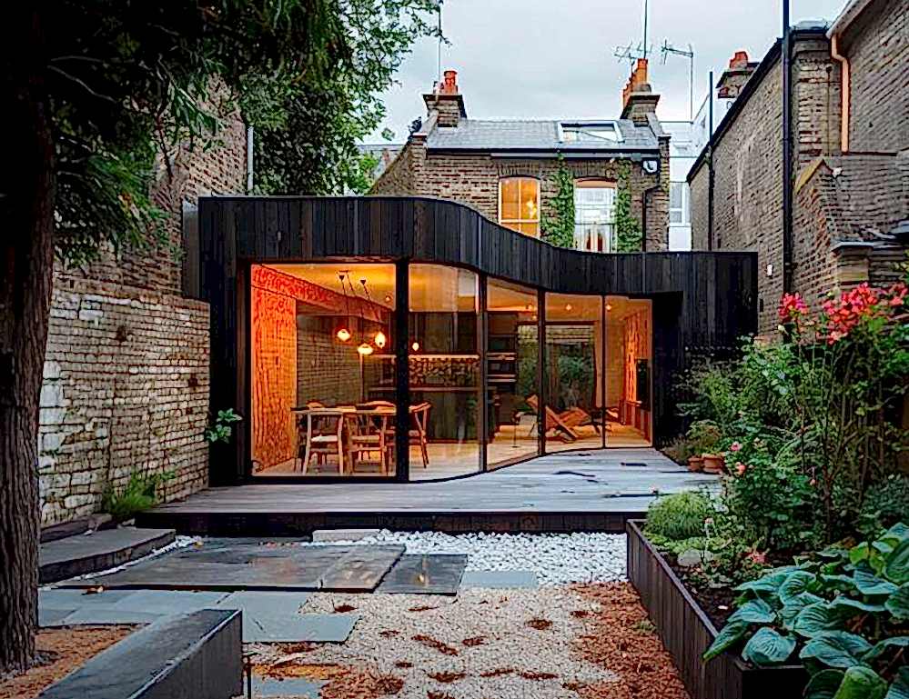 Rear view of a Victorian London home featuring a contemporary timber-clad extension with triple-glazed sliding doors, designed to EnerPHit standard for low energy use, airtightness, and sustainable performance while respecting the original architecture.