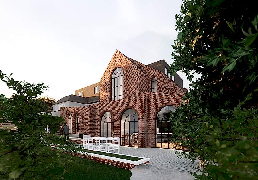A sustainably retrofitted brick building in London by RISE Design Studio, featuring arched windows, contemporary extensions, and a landscaped garden – showcasing the harmony between heritage architecture and modern low-energy design.