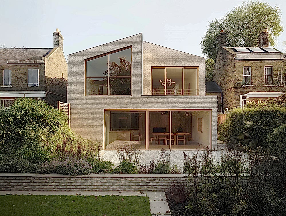 Rear view of a sustainable, low-energy home by RISE Design Studio in London, featuring a sculpted brick form, triple-glazed windows, and garden-facing living spaces designed for comfort, daylight, and passive environmental performance.