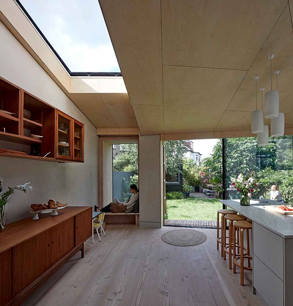 Interior of a low-energy deep retrofit home by RISE Design Studio featuring natural timber finishes, large skylight, MVHR-integrated design, and garden connection through full-height glazing.