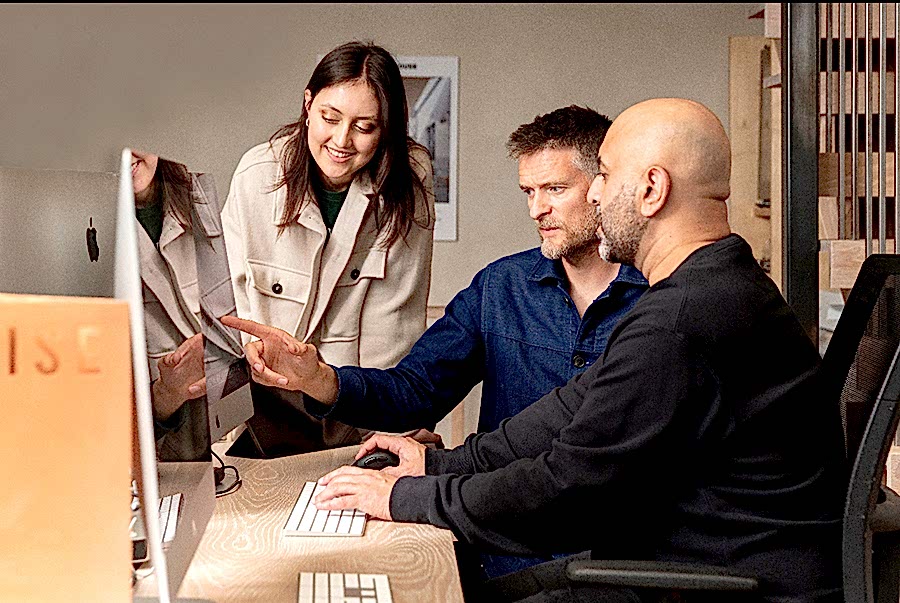 Directors Sean Ronnie Hill and Imran Jahn of RISE Design Studio collaborating with a team member at their London studio, reviewing architectural designs on screen. The image captures the studio’s hands-on, collaborative approach to purpose-led architecture