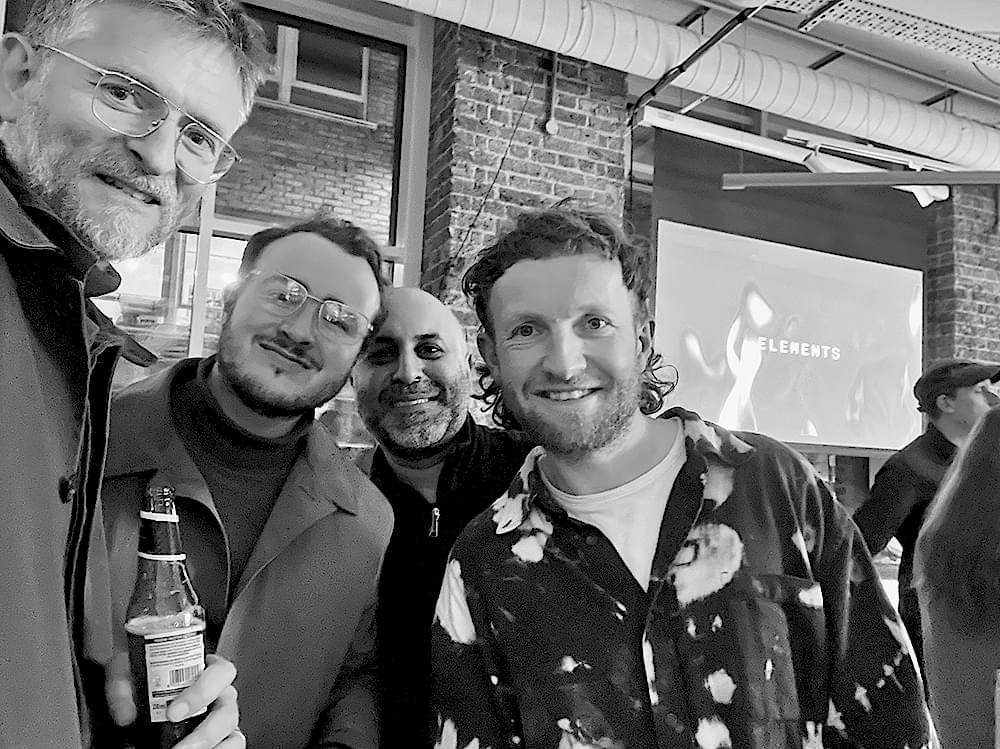 Douglas McMaster of Silo, Max McDonagh of AKT II, and Sean Ronnie Hill and Imran Jahn of RISE Design Studio standing together at Solus Tiles, discussing zero-waste design and sustainable architecture.