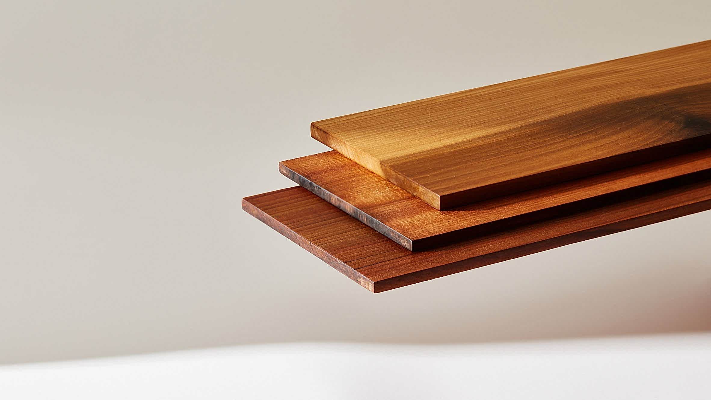 A detailed view of three stacked Superwood planks in varying warm tones, showcasing the fine grain and engineered density of this sustainable, high-performance timber alternative developed for low-carbon architectural applications.